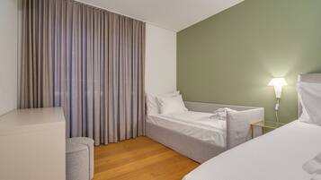 A hotel room with a bed, a seating area, a lamp, and a window with curtains.
