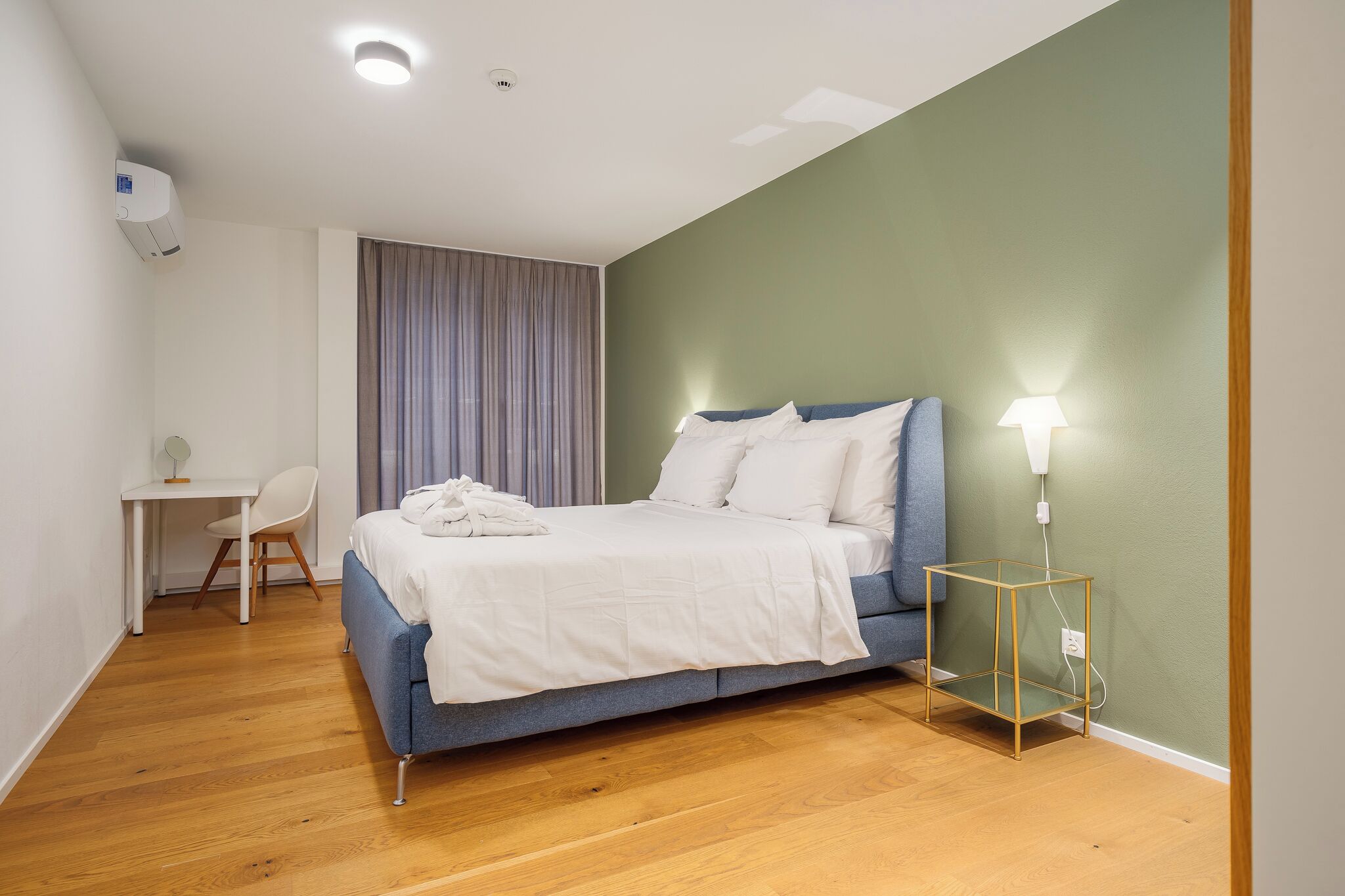 A bedroom with a bed, a desk, and a chair.