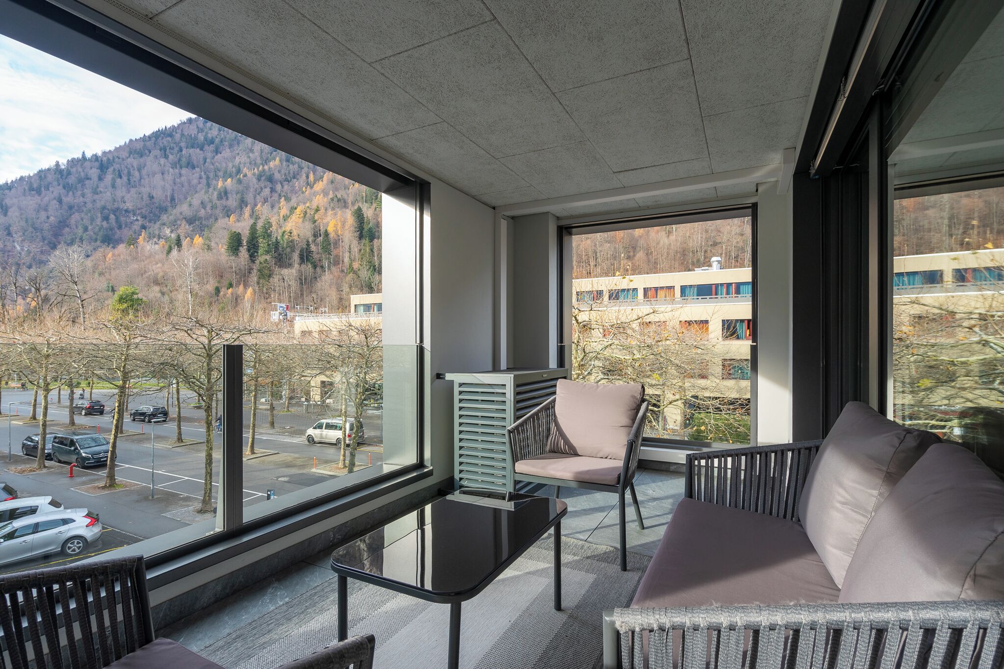 A modern room with large windows, a sofa, a chair, and a table.