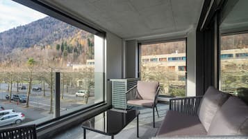 Una habitación moderna con ventanas amplias, un sofá, una silla y una mesa.