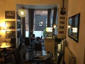 A dining area with a round table, chairs, and a hanging light fixture. - Hendham House Hotel (Manchester)