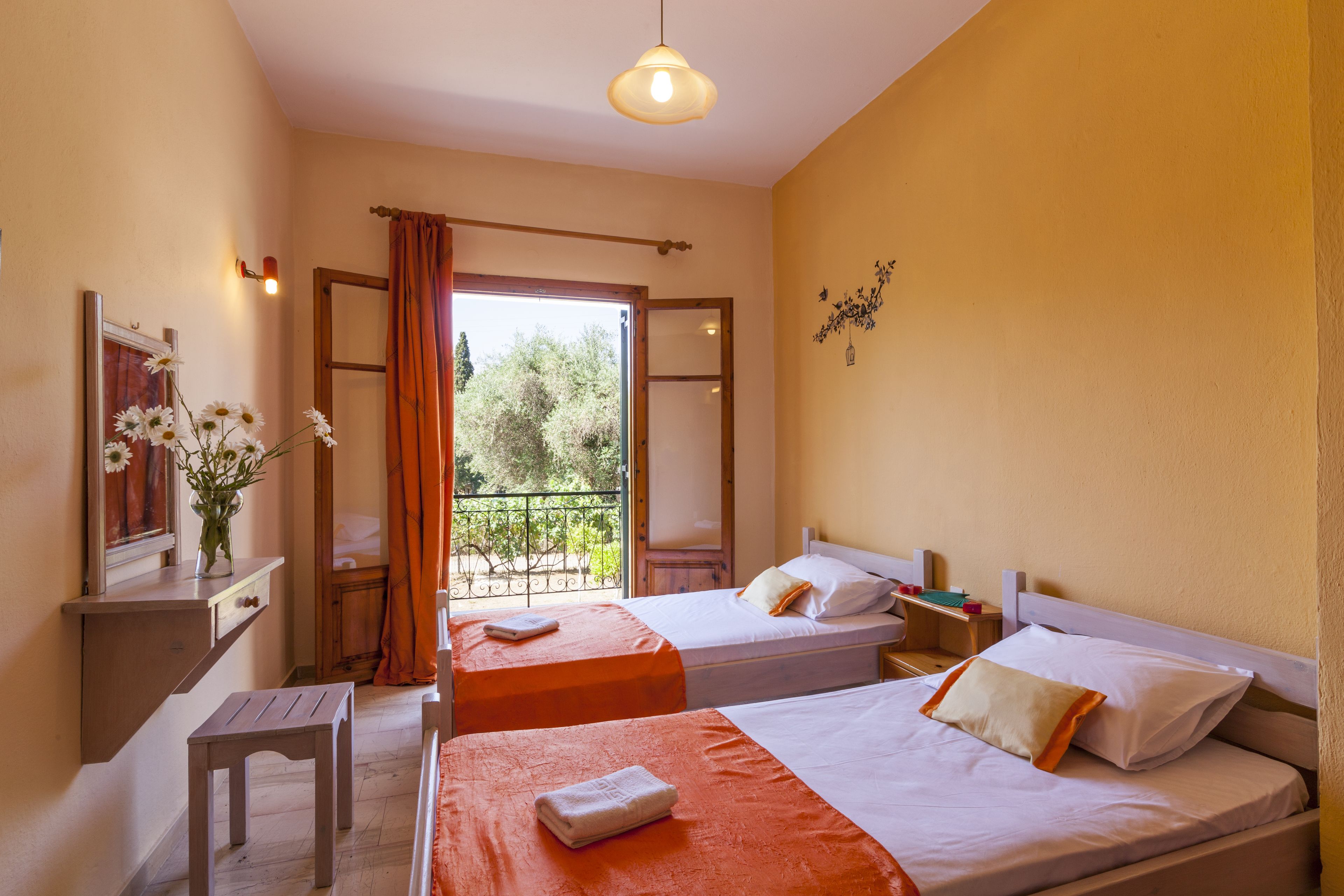 Quarto de hotel com duas camas, uma mesa pequena, mesa de cabeceira e uma janela com cortinas.