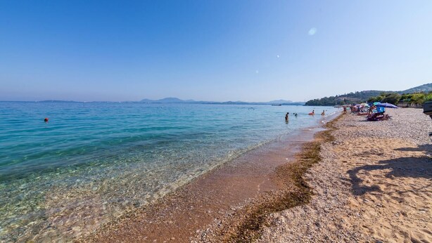 A beach with clear water, pebbles, and people. - Ipsos Marias Apartments By Konnect (Corfu)