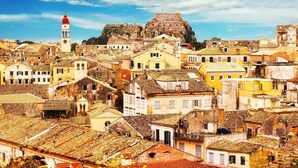 A densely packed urban area with historic buildings, a prominent clock tower, and a fortified hilltop structure. - Ipsos Marias Apartments By Konnect (Corfu)