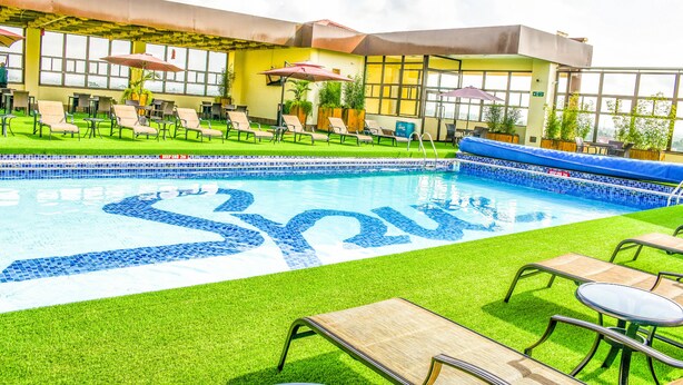 A rooftop pool area with lounge chairs, umbrellas, and a pool with a blue mosaic design. - Verona Hotel & Conference Center (Ruiru)