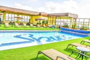 A rooftop pool area with lounge chairs, umbrellas, and a pool with a blue mosaic design.