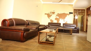 A modern living room with leather sofas, a glass coffee table, and a world map on the wall. - Verona Hotel & Conference Center (Ruiru)