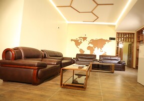 A modern living room with leather sofas, a glass coffee table, and a world map on the wall.