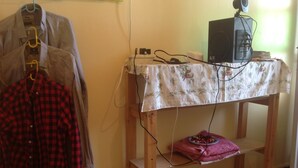 Una habitación con una mesa de madera cubierta por un mantel floral, un televisor encima y un altavoz en la pared.