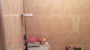 Un baño con inodoro, un estante con artículos de aseo y una cesta de frutas y verduras.