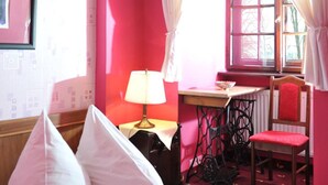 A room with a bed, a desk, a chair, and a window with curtains. - Zamek Dobra (Dobroszyce)