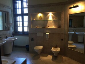 Un baño con dos lavabos, un bidé, un inodoro y un espejo.
