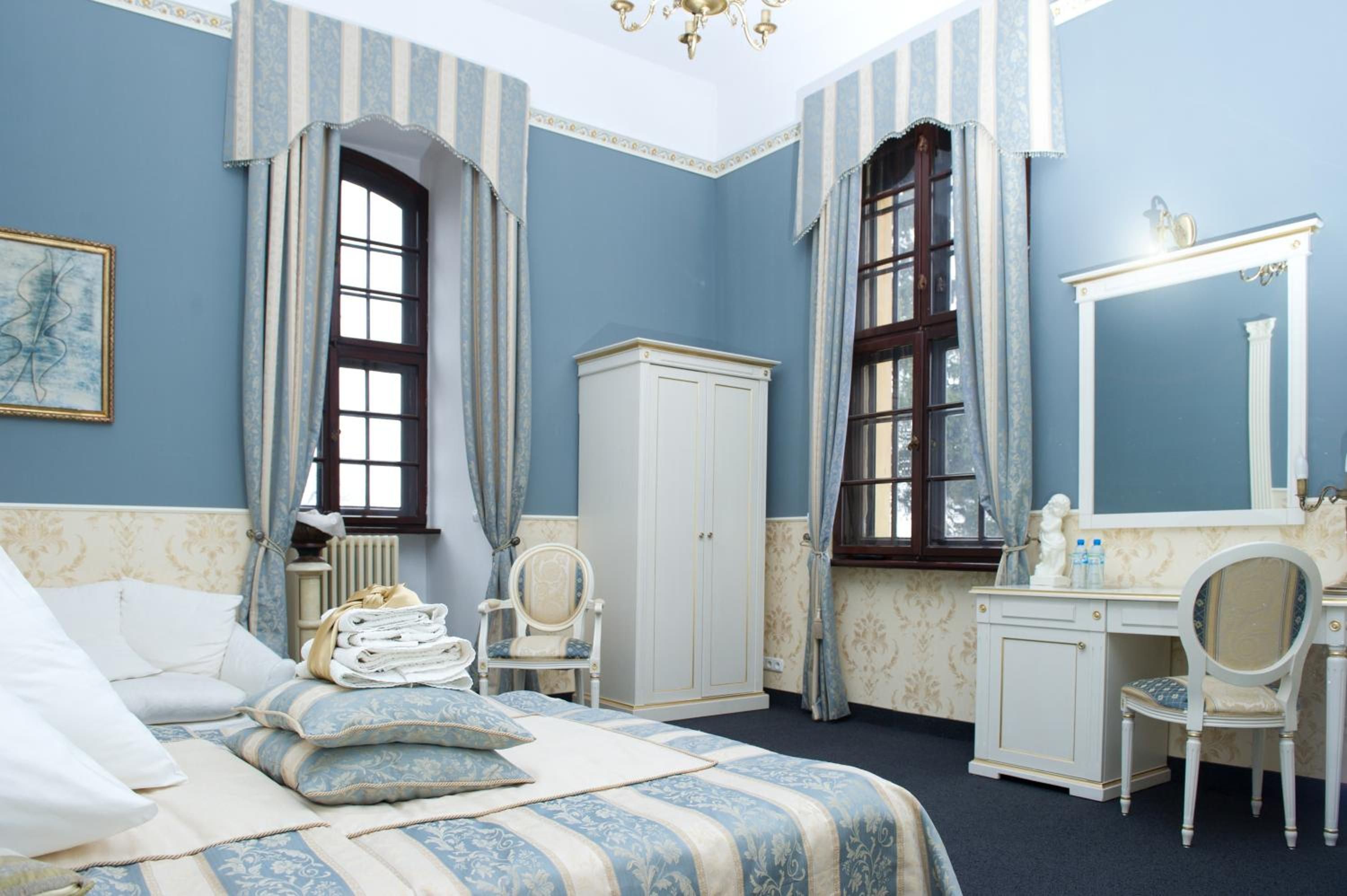 Ein Schlafzimmer mit einem Bett, einem Schminktisch, einem Sessel und einem großen Spiegel.