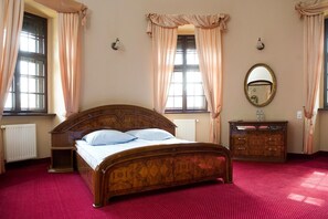 Un dormitorio con una cama de madera, un aparador, un espejo y un radiador.