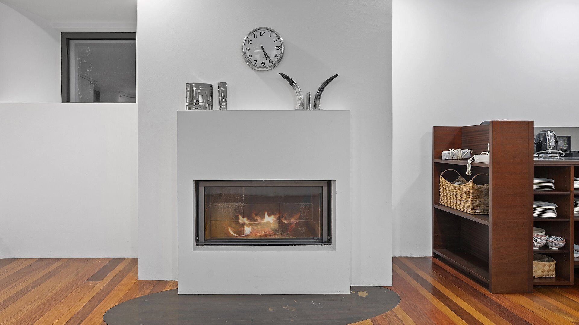 Un salon moderne avec une cheminée, une horloge et une bibliothèque.