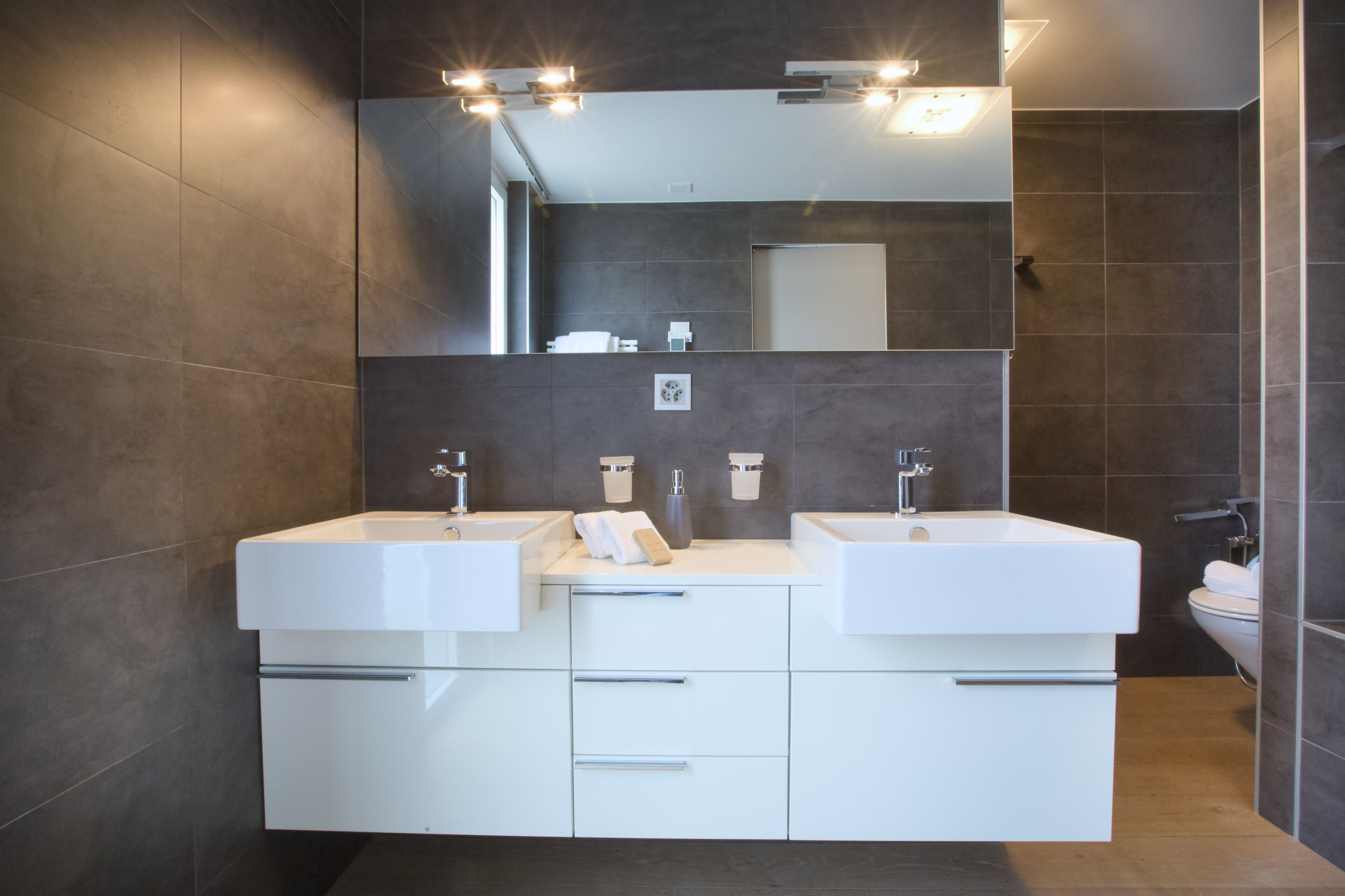 Un baño moderno con dos lavamanos, un espejo grande y una zona de ducha.