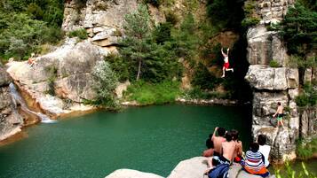 A natural rock formation with a river below, surrounded by greenery.