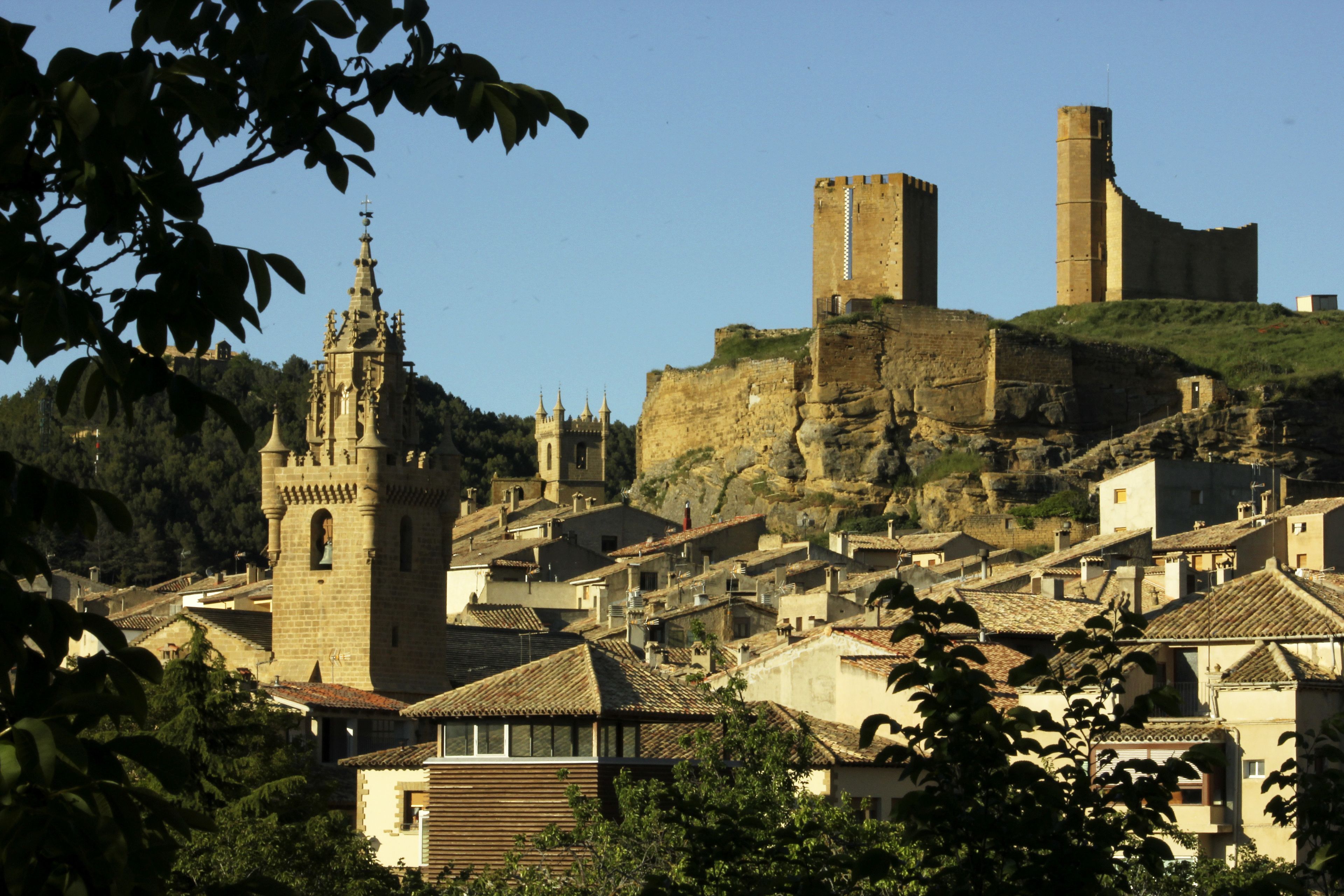 Un pueblo histórico con una torre destacada y una gran fortificación en una colina.