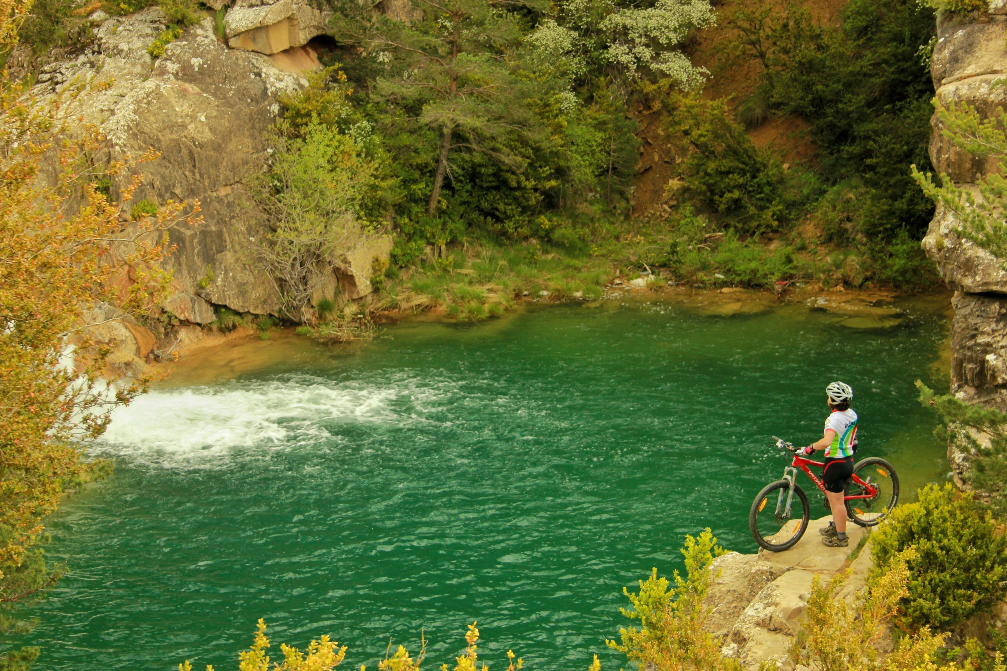 Een persoon op een mountainbike met uitzicht op een rivier.