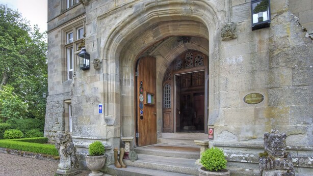 A stone building with a wooden door and steps leading up to it. There are two stone lion statues on either side of the entrance. - Tillmouth Park Country House Hotel (Cornhill on Tweed)