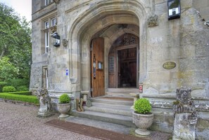 A stone building with a wooden door and steps leading up to it. There are two stone lion statues on either side of the entrance. - Tillmouth Park Country House Hotel (Cornhill on Tweed)