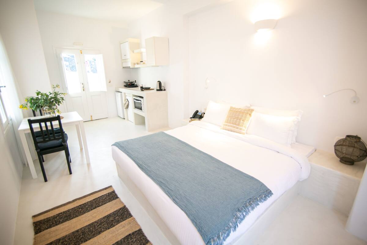 Ein Schlafzimmer mit Bett, Nachttisch und Schreibtisch. Im angrenzenden Raum befindet sich ein Schreibtisch und Stuhl.