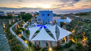 A coastal hotel with a pool, outdoor seating, and a view of the sea. - Apanomeria Residence (Santorini)