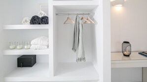 A clean, white bathroom with a towel rack, a hanging towel, and a small table with a candle and a book. - Apanomeria Residence (Santorini)