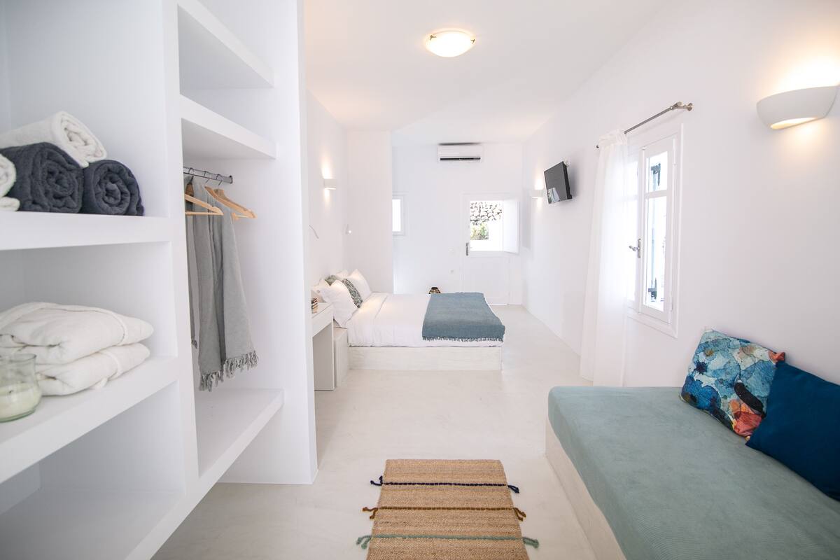 Ein modernes, helles Zimmer mit einem Bett, einer Couch und einem Kleiderschrank.