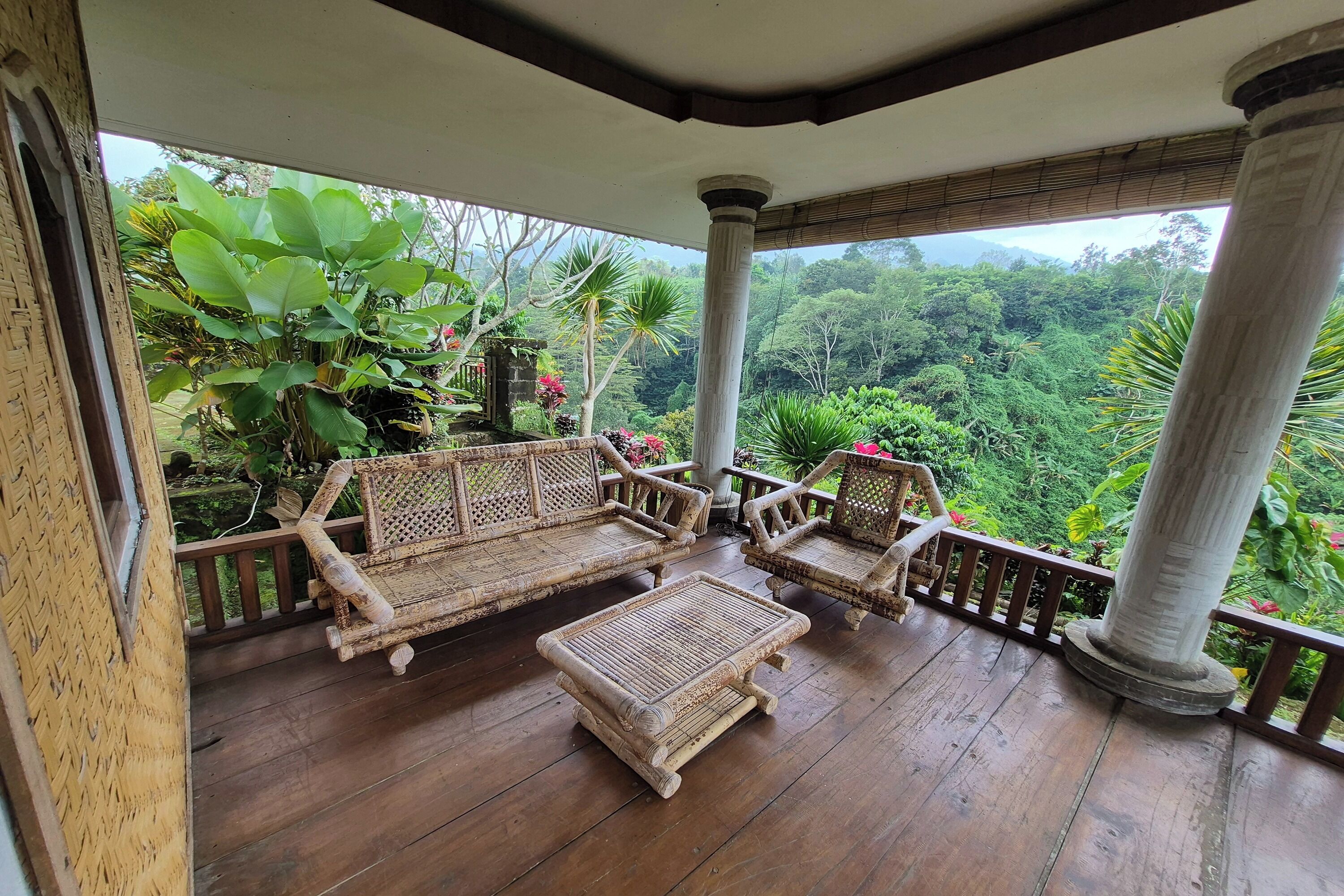 A wooden deck with wicker furniture and a view of lush greenery.
