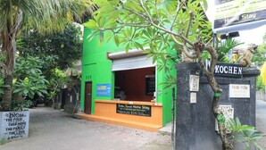 A green building with a sign for "Kubu Tanjuh Home Stay" and a "Laundry Service" sign. - Kubu Turah Homestay (Kedonganan)