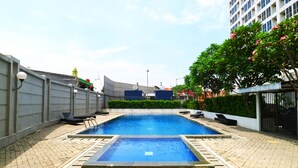 Una piscina en la azotea con vista a un edificio de gran altura al fondo.