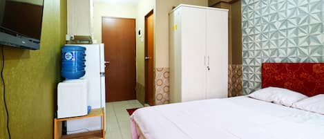 Una habitación de hotel con cama, armario, televisor y dispensador de agua.