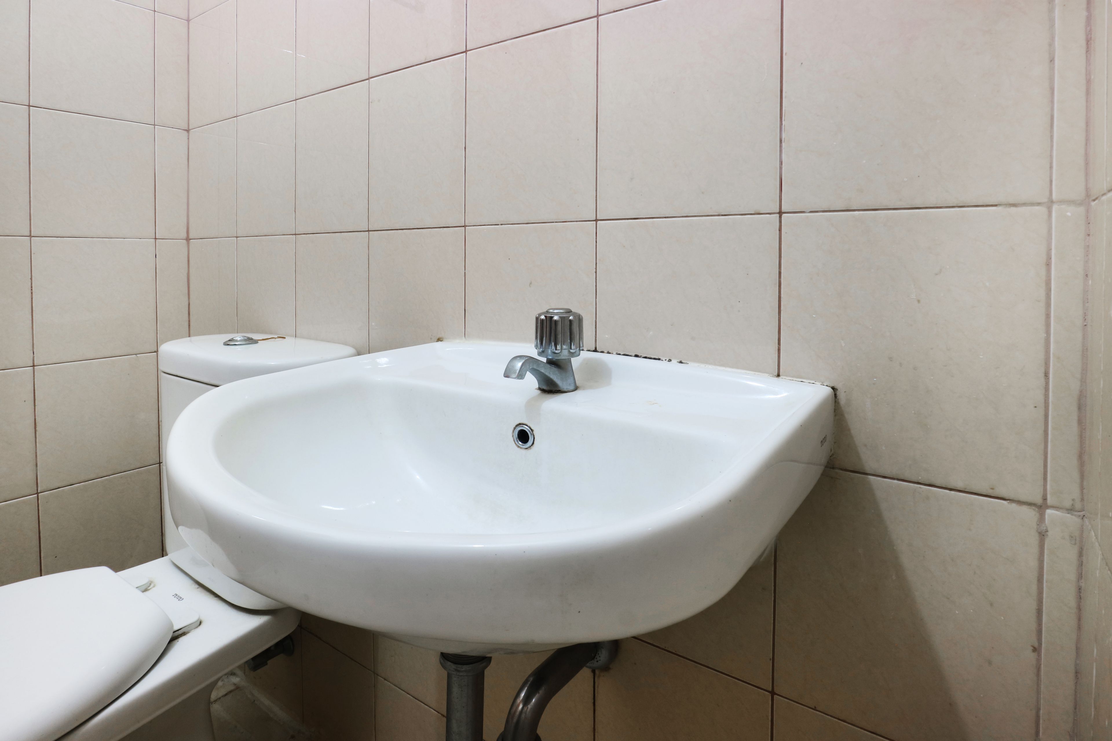 A bathroom with a white sink, toilet, and tiled walls.