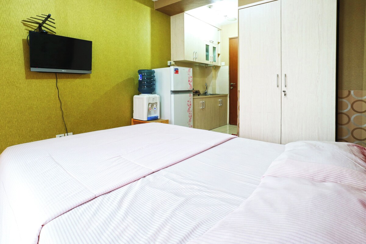 Habitación de hotel con cama, televisor en la pared, refrigerador y dispensador de agua.