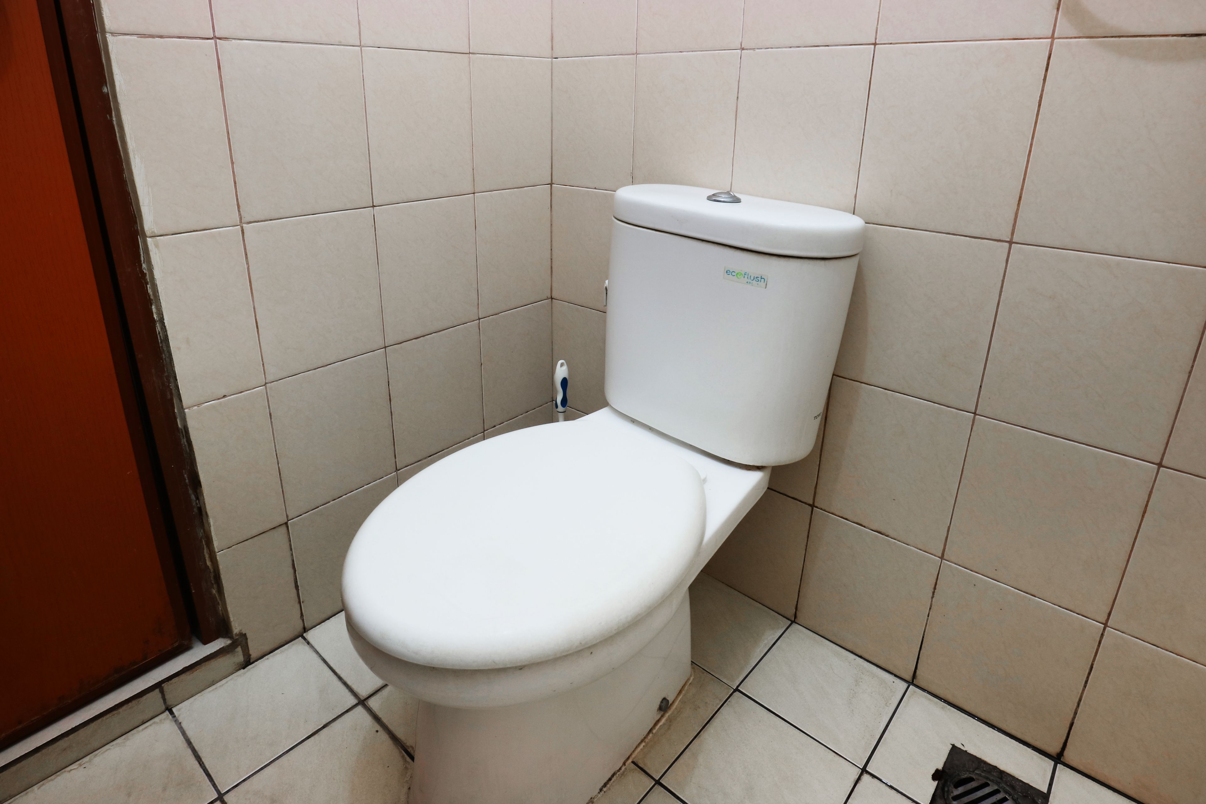 Des toilettes blanches, dotées d’une poignée de chasse d’eau et d’un autocollant sur le réservoir.