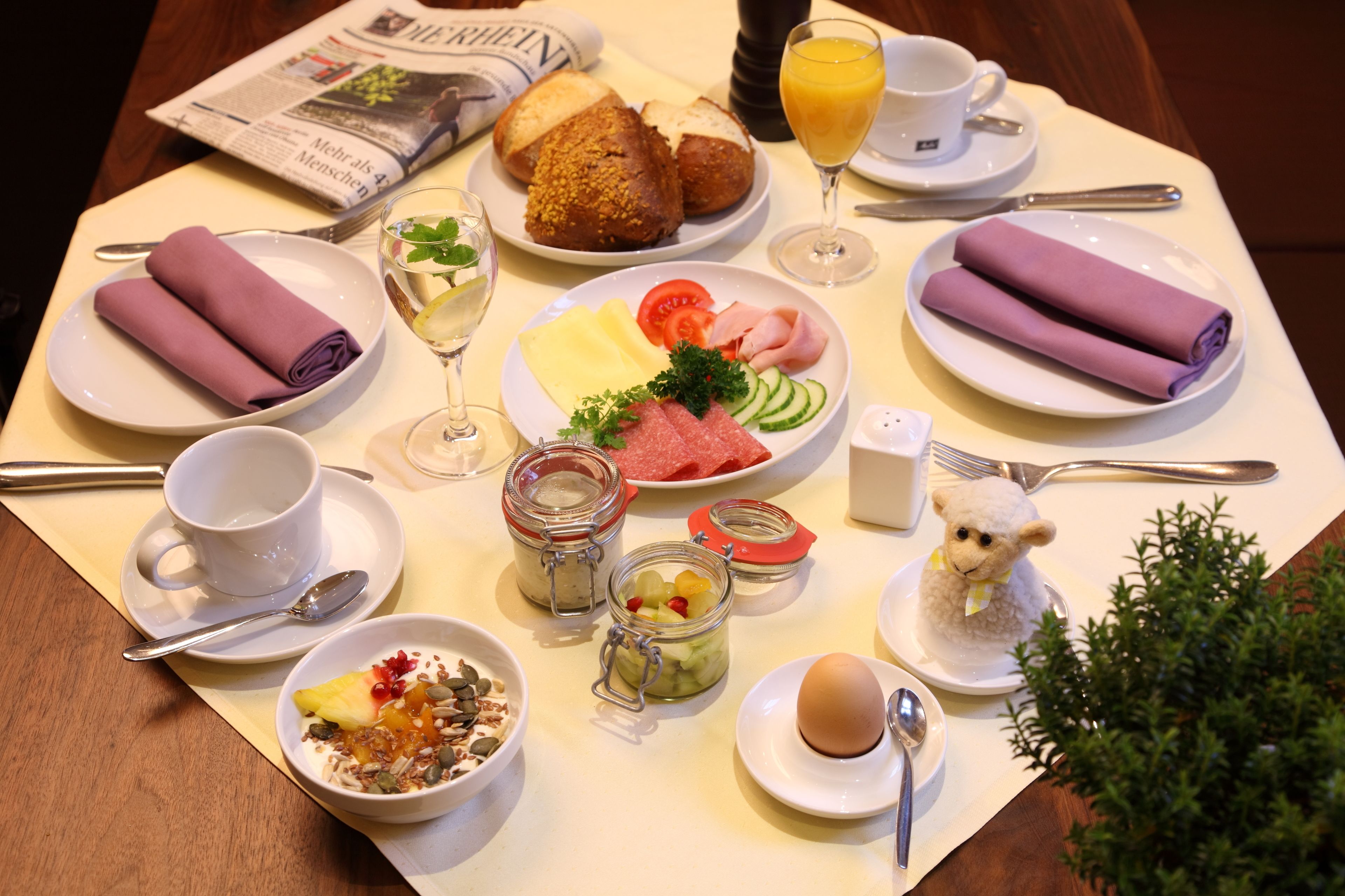 Una mesa de desayuno con diversos platos, como pan, fruta y huevos.