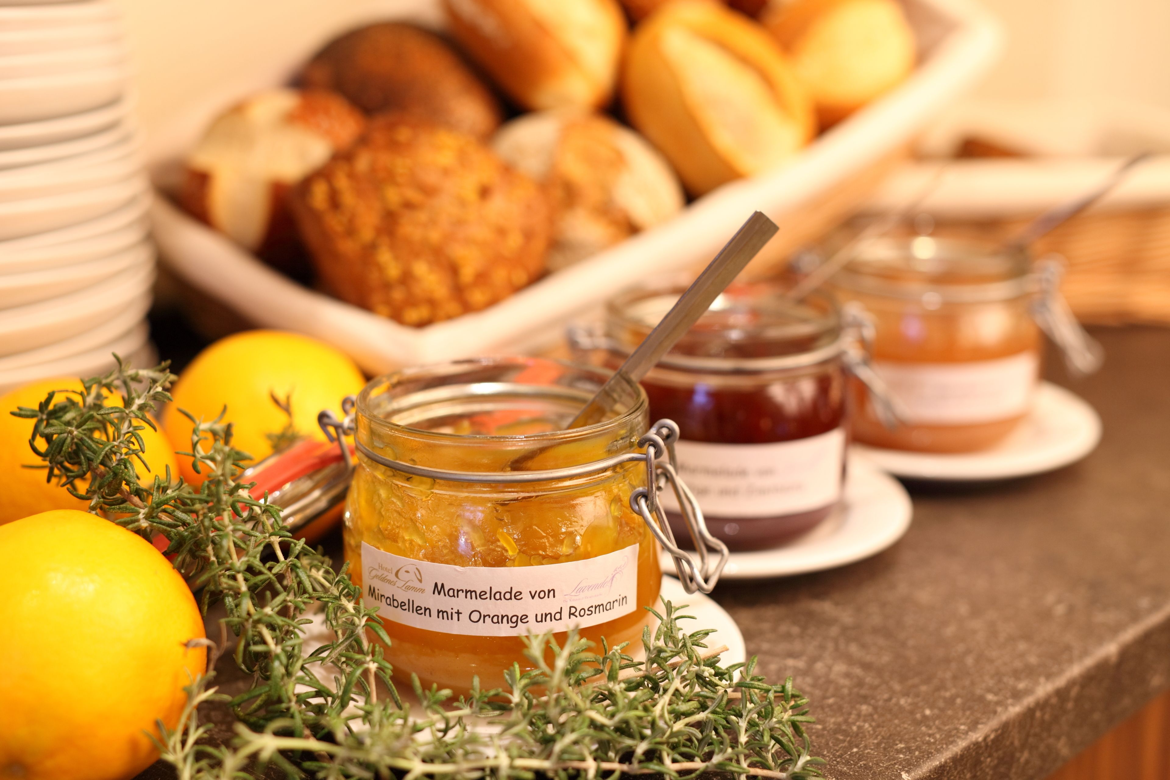 Een tafel met potten marmelade, citroenen en rozemarijn.