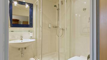 Un baño moderno con ducha de vidrio, lavamanos blanco y retrete.