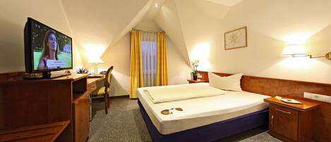 A hotel room with a bed, a desk, a television, and a nightstand.