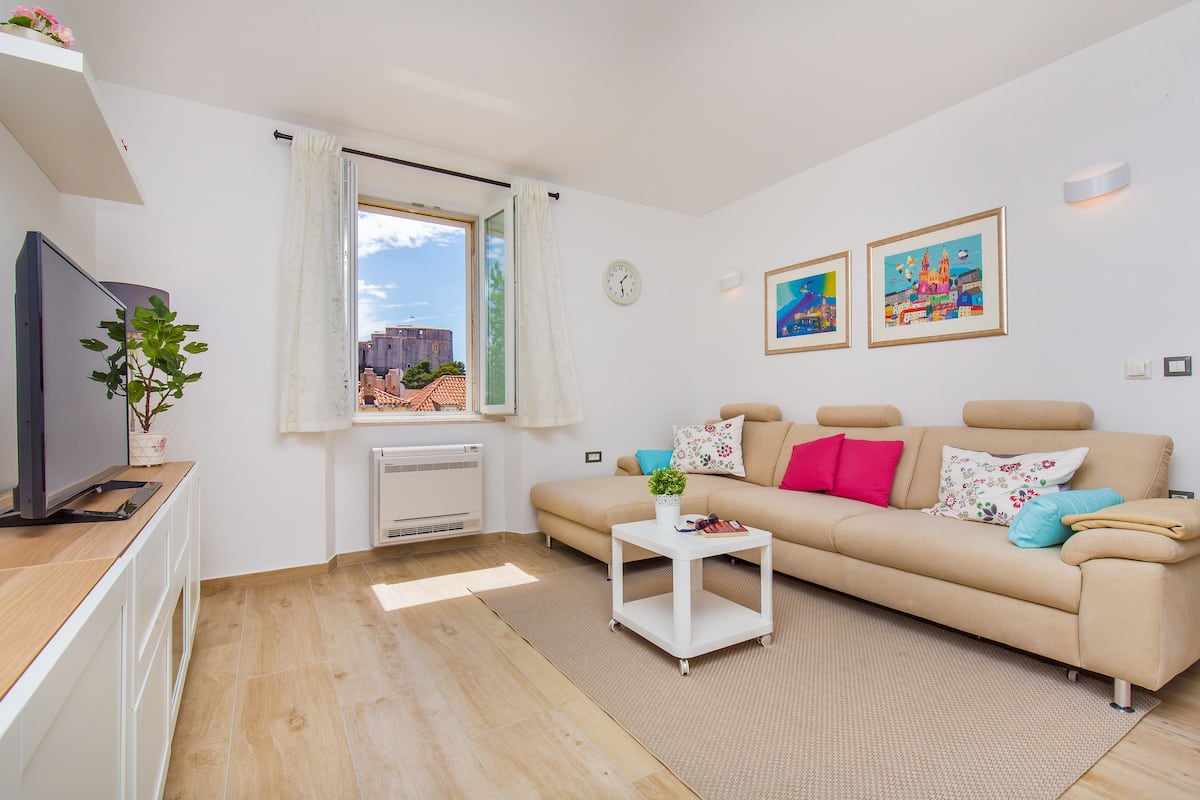 A modern living room with a beige sofa, a white coffee table, and a flat-screen TV.