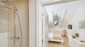 Ein modernes Badezimmer mit Dusche, einem Bett, einem Nachttisch und einer Kommode.