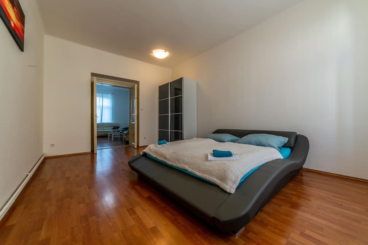 A bedroom with a bed, a wardrobe, and a door leading to another room.