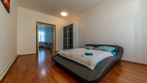 A bedroom with a bed, a wardrobe, and a door leading to another room.