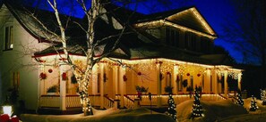 Ein Haus mit Veranda, geschmückt mit Lichtern und Weihnachtsdekorationen.