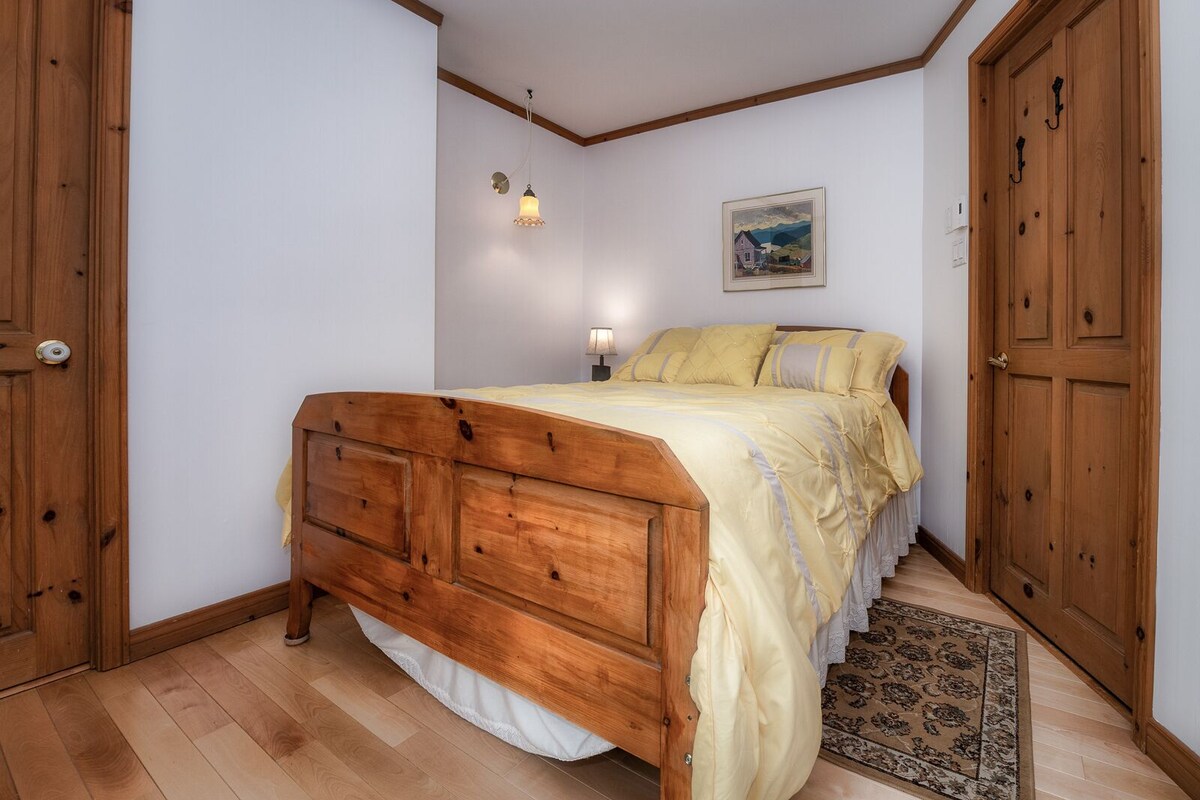 Ein Schlafzimmer mit einem hölzernen Bett, einem Nachttisch, einer Lampe, einem gerahmten Bild an der Wand und einem Holzschrank.
