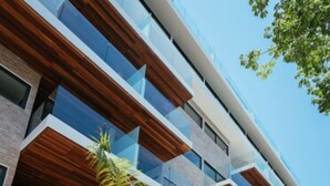 A modern multi-story building with balconies, palm trees, and a paved area. - Trendy 1BR Apartment in Cruz con Mar brand new building by Happy Address (Playa del Carmen)