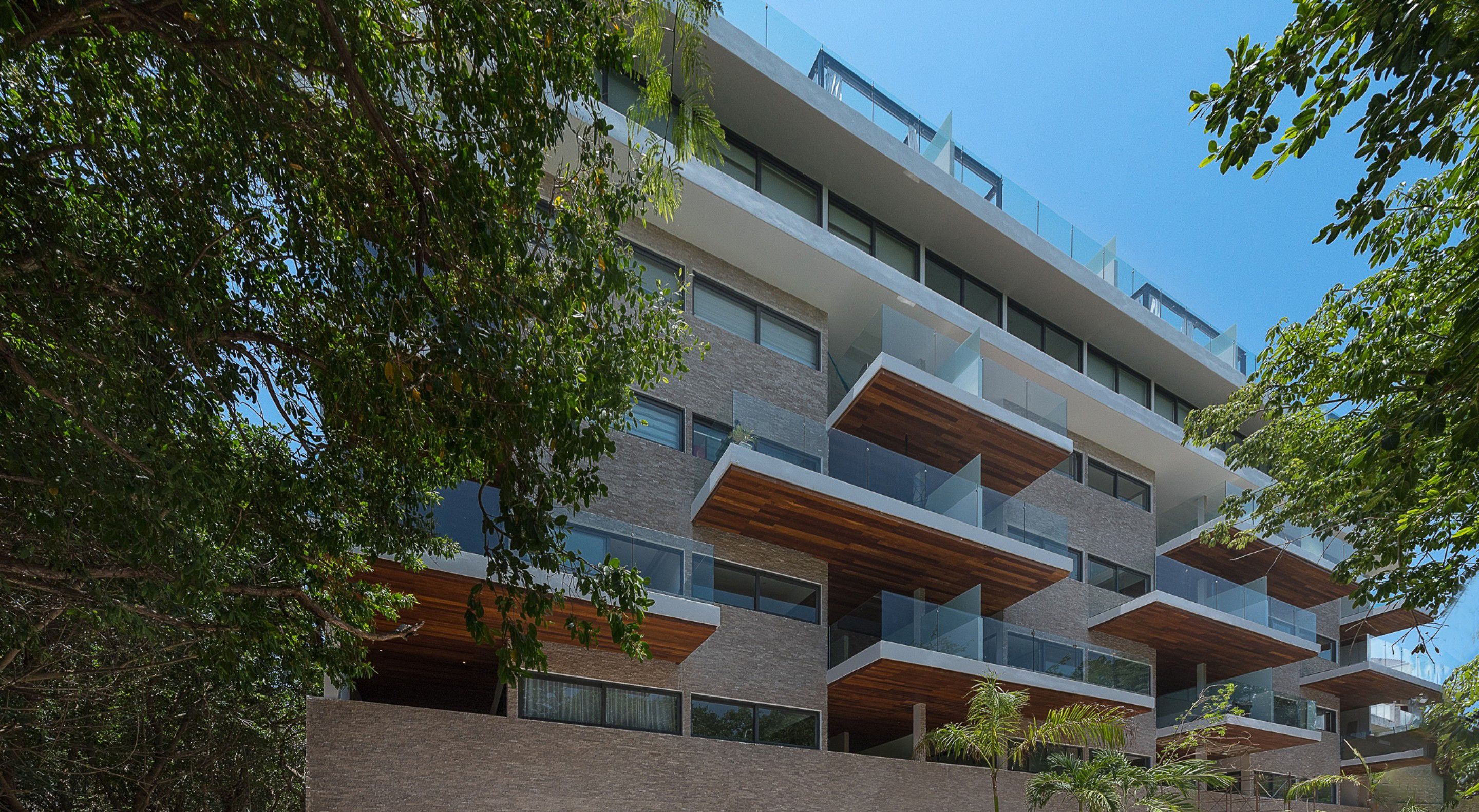 A multi-story building with balconies, large windows, and a brick facade.