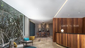 A modern reception area with a wooden wall, a reception desk, and a seating area with a round table and chairs. - Full Stylish 2BR apartment in heart of town by Happy Address (Playa del Carmen)
