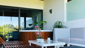 A modern outdoor seating area with a wooden bench, white tables, and a grey sofa. - Full Stylish 2BR apartment in heart of town by Happy Address (Playa del Carmen)
